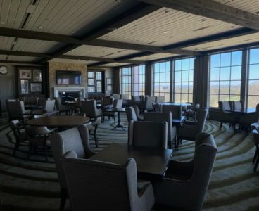 dining area: wooden tables, dining chairs, and fireplace in the background