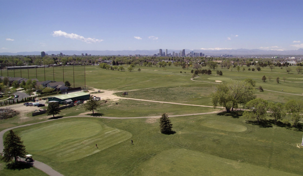aerial of golf course with city and mountains in the background