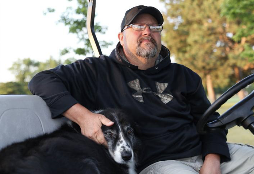 man sitting in golf cart with a dog