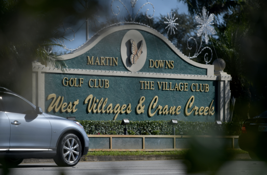 golf course sign with passing car.